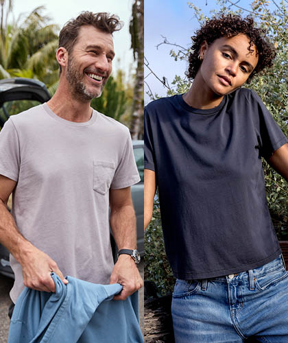 Two people standing outdoors, one holding a blue shirt, with trees and a car in the background.