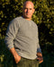 Kelly Slater wearing a heather grey crewneck sweater.