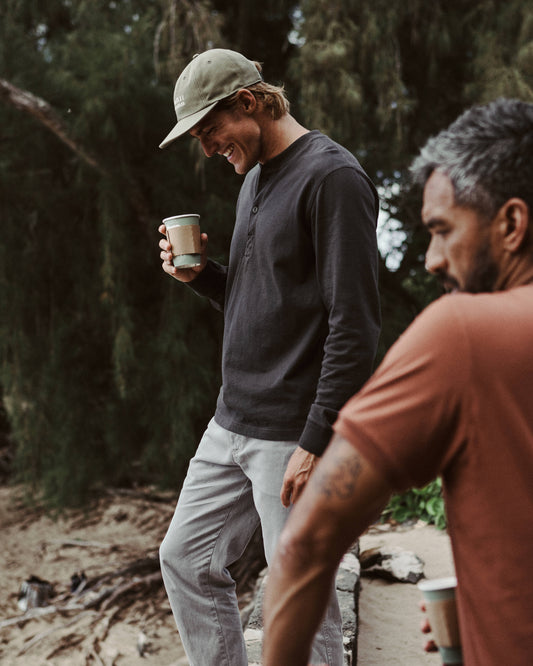 Man wearing black henley shirt holding a cup
