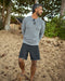 Man wearing black boardshorts and a gray sweater on the beach