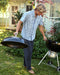 Guy wearing blue patterned shirt moving a BBQ