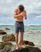 Man wearing blue boardshorts with a drawstring waistband at the beach.