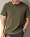 Man wearing olive green short sleeve t-shirt in a studio