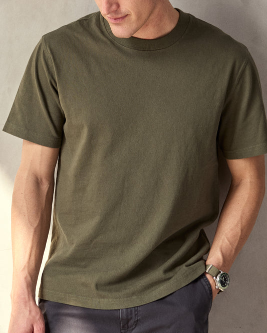 Man wearing olive green short sleeve t-shirt in a studio