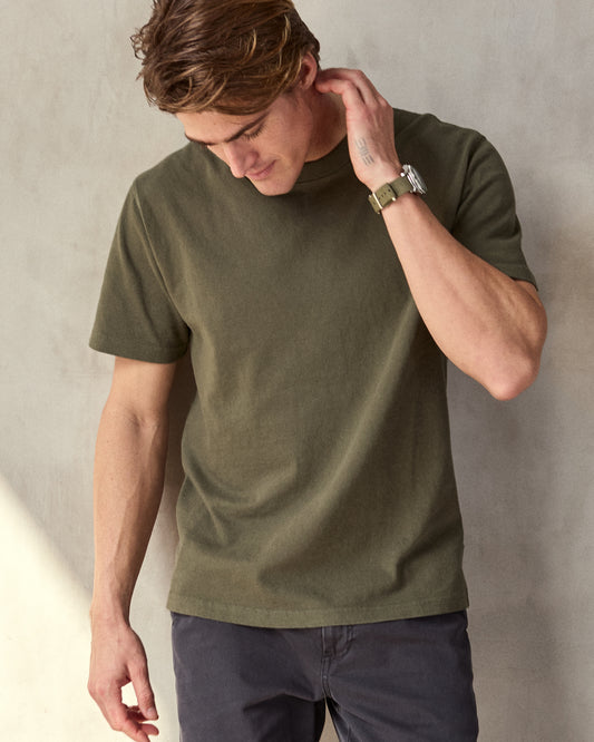 Man wearing olive green short sleeve t-shirt in a studio