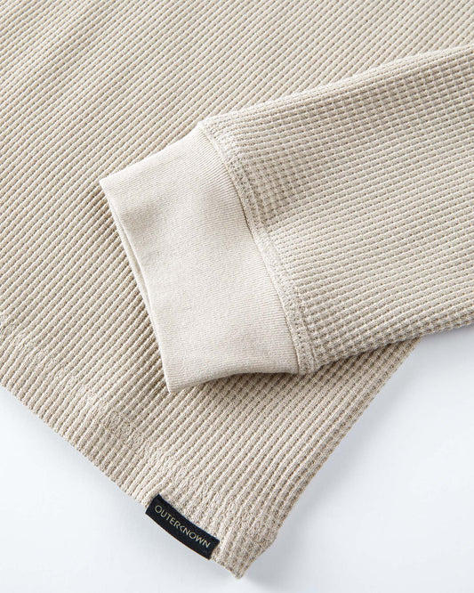 Beige textured fabric with a brand label on a white background