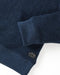 Closeup of navy blue crewneck sweatshirt made from terry toweling fabric, with a visible brand tag on the lower side.