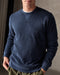 Man wearing a navy blue crewneck sweatshirt made from terry toweling fabric, with a visible brand tag on the lower side.