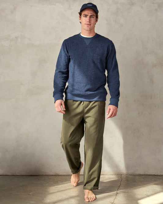 Man wearing a navy blue crewneck sweatshirt made from terry toweling fabric, with a visible brand tag on the lower side.