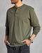 Man wearing a long-sleeved green henley shirt with a ribbed neckline and cuffs, featuring a minimal 2-button placket and flatlock seams.