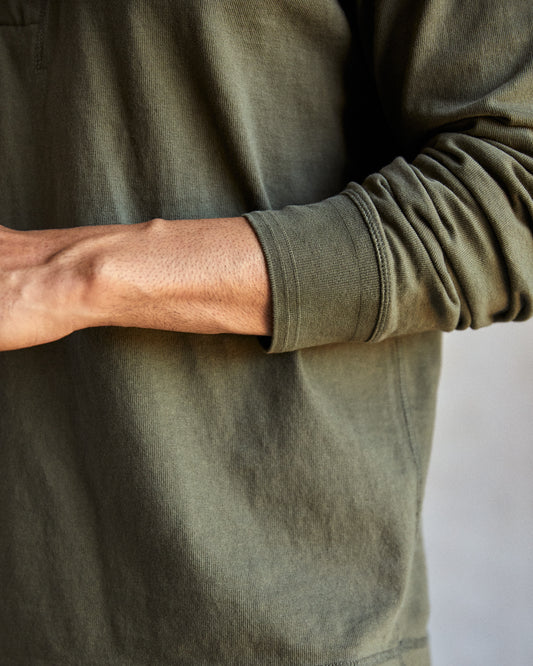 Closeup of long sleeve of green henley shirt being worn by a man