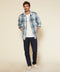 Blue plaid blanket shirt worn open over a white tee with dark jeans