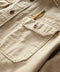 Closeup of a long-sleeved, button-up, beige utilitarian shirt with chest pockets.