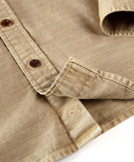 Closeup of logo on the beige utilitarian shirt