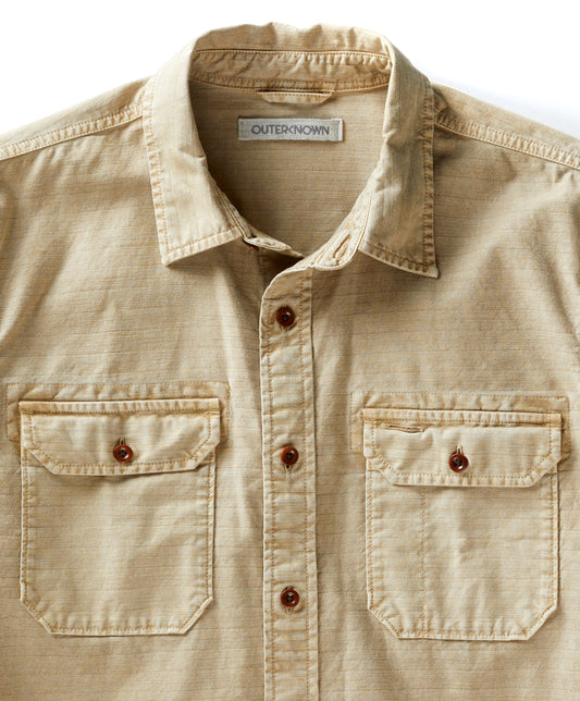 A long-sleeved, button-up, beige utilitarian shirt with chest pockets.