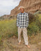 Man standing in a natural landscape with cliffs and wildflowers