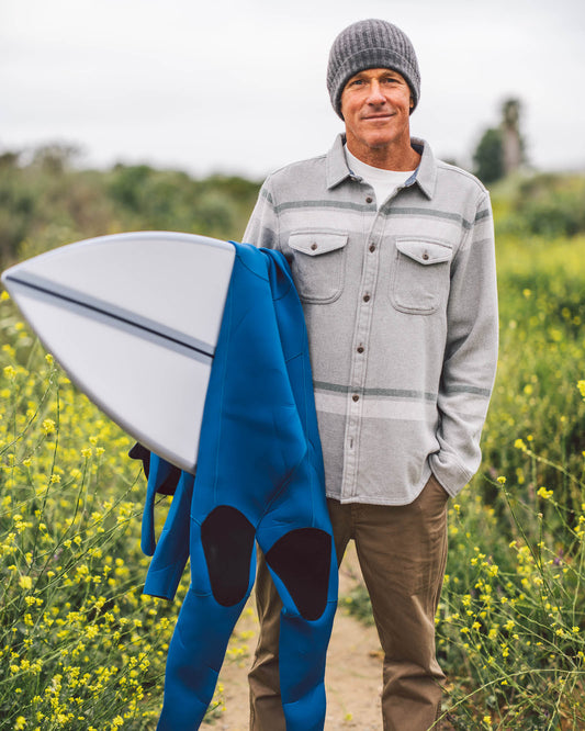 Man holding a surfboard with a blue cover in a field