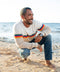 Outerworn nostalgic sweater on model; oatmeal knit with rainbow stripe band