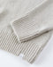 Close-up of a folded light beige knit blanket on a white surface