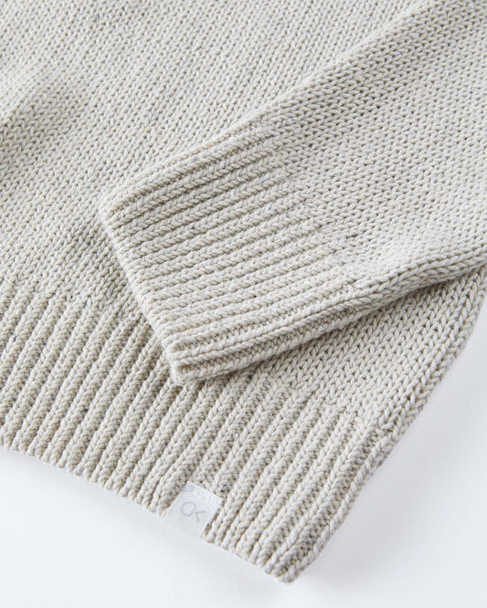 Close-up of a folded light beige knit blanket on a white surface