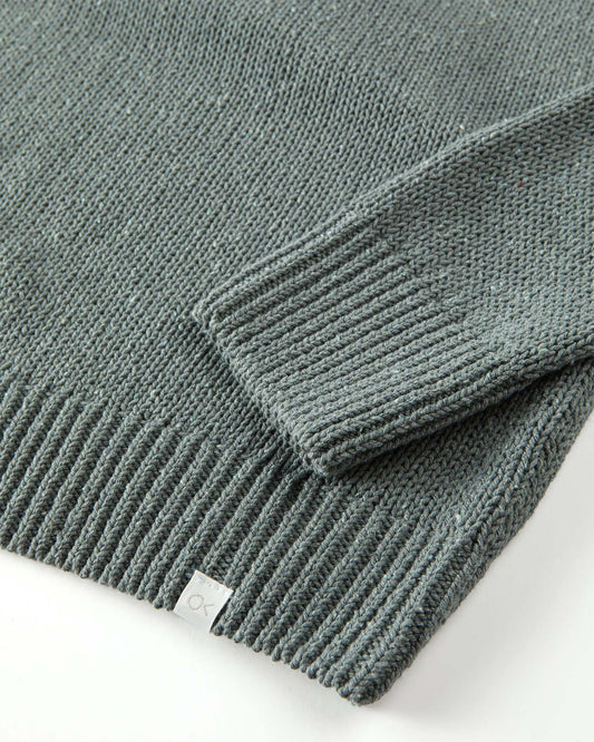 Close-up of a green knitted sweater with a brand label on a white background