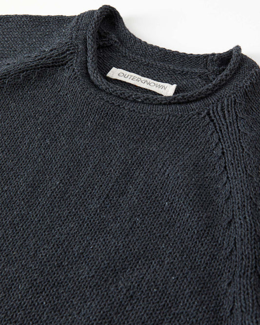 Close-up of a black sweater with a brand label on a white background