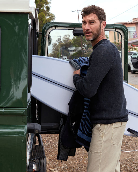 Man standing next to a vehicle with an open door, holding a jacket.