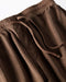 Close-up of brown sweatpants with drawstring waistband on a white background