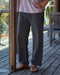 Person wearing black sweatpants and sandals on a wooden deck.