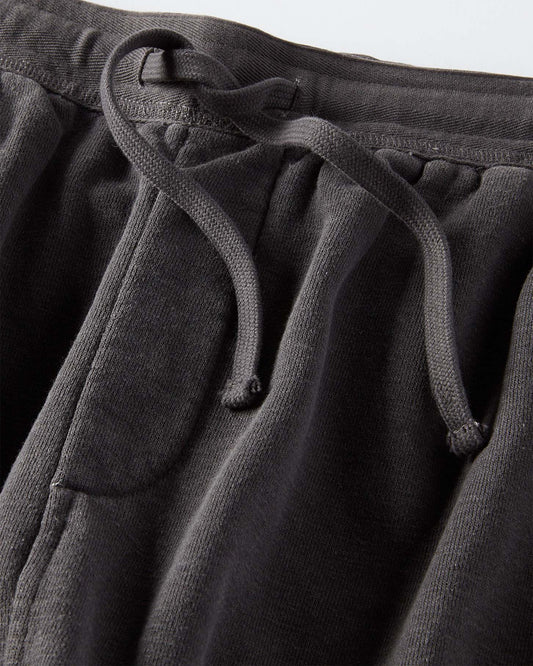 Close-up of black sweatpants with a drawstring on a light gray background