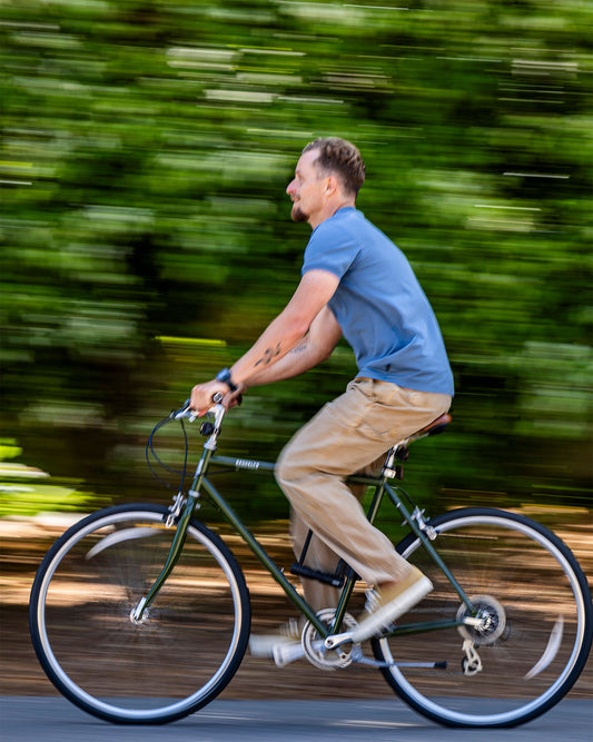 Man riding a bicycle on a road with blurred greenery in the background