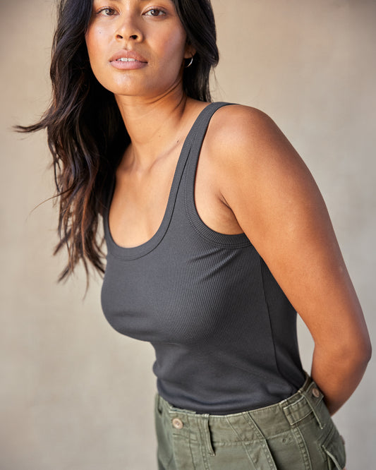 A woman wearing a gray ribbed tank top and green shorts.