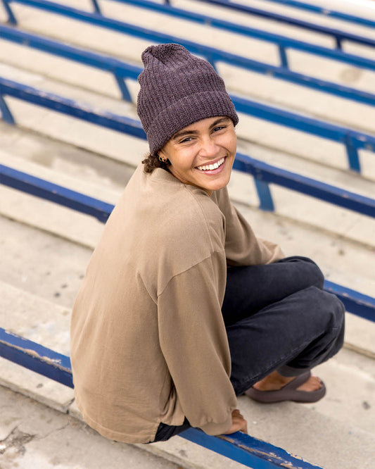 Person wearing a beanie and sitting on bleachers