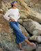 Woman in a white shirt and blue jeans standing on rocky terrain