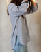 A woman wearing a black and white pinstriped oversized shirt and light blue jeans.