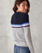 A woman wearing a striped sweater with a crew neckline, where the stripes feature shades of gray, blue, and purple, and the brand logo 'OK' is visible on the chest.