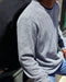 Man wearing gray crew neck sweater made from a blend of organic cotton and recycled polyester.