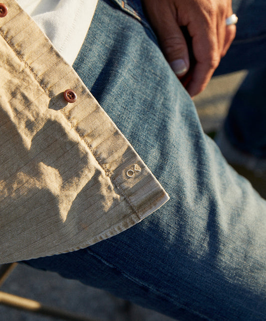 Closeup of a long-sleeved, button-up, beige utilitarian shirt with chest pockets.
