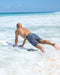 Kelly Slater wearing boardshorts with a geometric pattern in shades of blue and light blue, featuring a drawstring waistband.