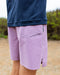 Man wearing purple boardshorts with a drawstring waist and branded detail on the upper left thigh.