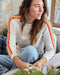 Woman wearing a sweater with rainbow stripes sitting on a couch.