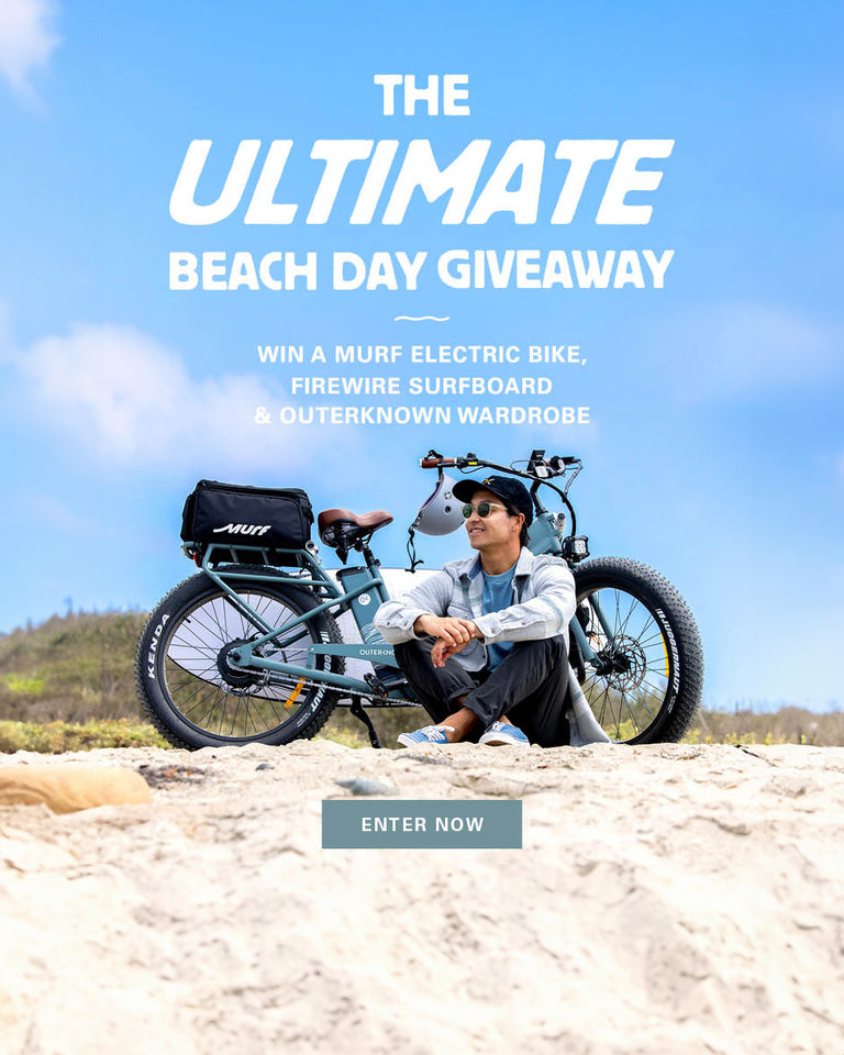 Promotional banner for an electric bike giveaway with a beach scene and text overlay that reads: The Ultimate Giveaway. Win a Murf electric bike, firewire surfboard & outerknown wardrobe. The button reads "enter now"
