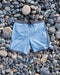 Light blue shorts with dark gray trim on a bed of pebbles