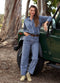 Woman in blue outfit standing next to a green jeep in a natural setting
