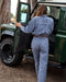 Person getting into a green off-road vehicle with trees in the background