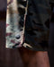 Camouflage-patterned boardshorts with a button on a dark background