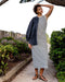 Woman in a striped dress standing outdoors with greenery around