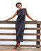 Woman in a gray dress standing on a wooden dock with a white background