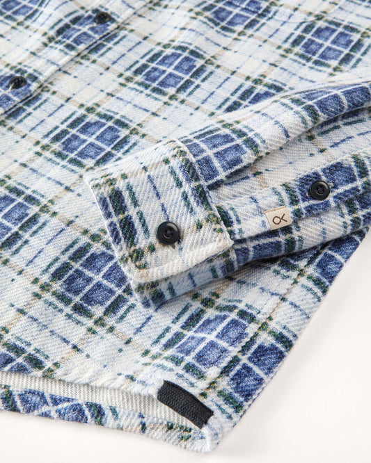 Closeup of sleeve of blue and white plaid blanket shirt.
