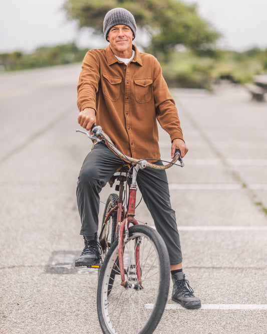 Man riding a bicycle on a paved road with trees in the background